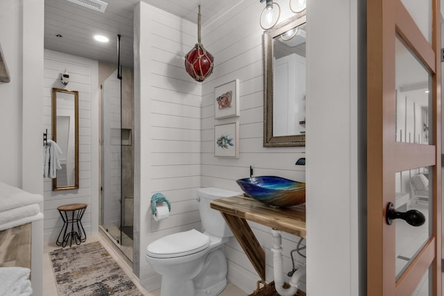 bathroom featuring toilet, wood walls, a shower stall, and a sink