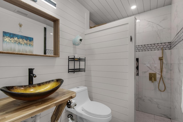 bathroom with wooden walls, a marble finish shower, visible vents, toilet, and a sink