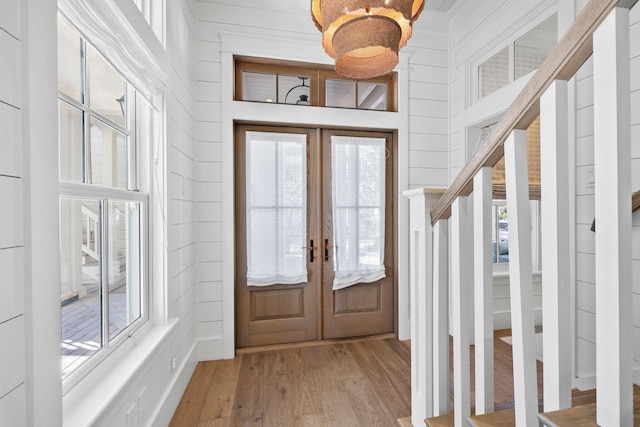 foyer featuring wood walls, french doors, and light hardwood / wood-style flooring