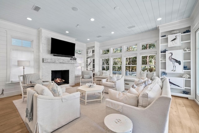 living room featuring light hardwood / wood-style flooring, a stone fireplace, wooden ceiling, and wood walls