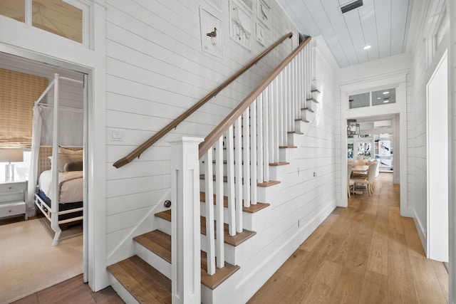 stairs with a wealth of natural light, wood-type flooring, and wood walls