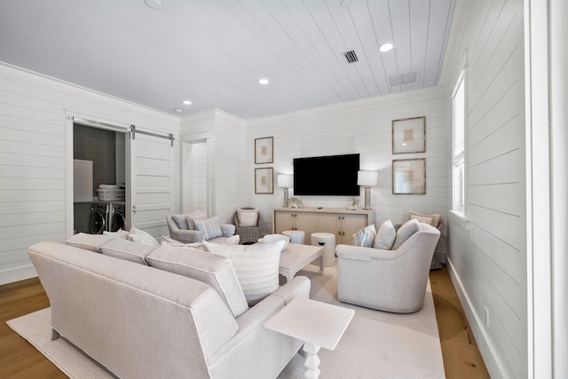 living room with a barn door, washer and clothes dryer, and light hardwood / wood-style floors