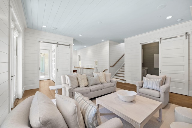 living room with a barn door, wood walls, and light hardwood / wood-style floors