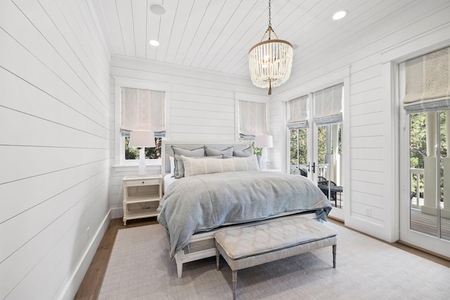 bedroom featuring hardwood / wood-style floors, access to outside, french doors, an inviting chandelier, and wooden walls