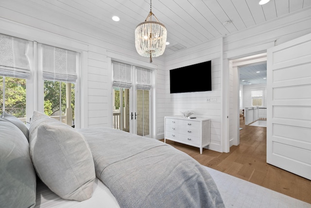 bedroom with multiple windows, dark hardwood / wood-style flooring, an inviting chandelier, and access to exterior