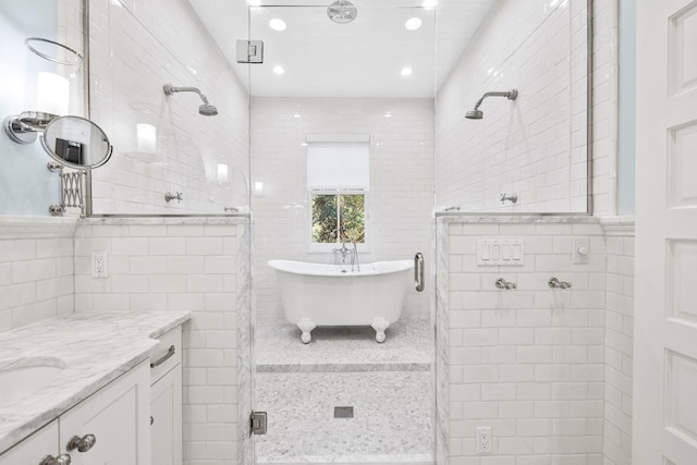 bathroom with shower with separate bathtub, vanity, and tile walls