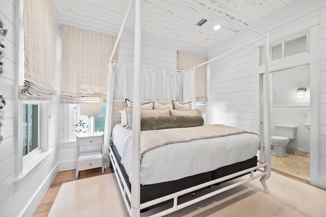 bedroom with hardwood / wood-style floors, ensuite bath, wooden walls, and wood ceiling