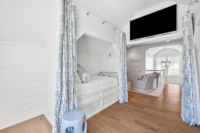 bedroom featuring wood walls, wood-type flooring, and lofted ceiling