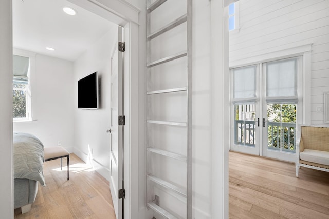 hall with light wood-type flooring and a healthy amount of sunlight