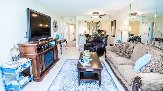 tiled living room featuring a fireplace and ceiling fan