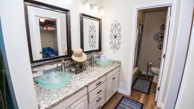 bathroom with wood-type flooring, vanity, toilet, and walk in shower