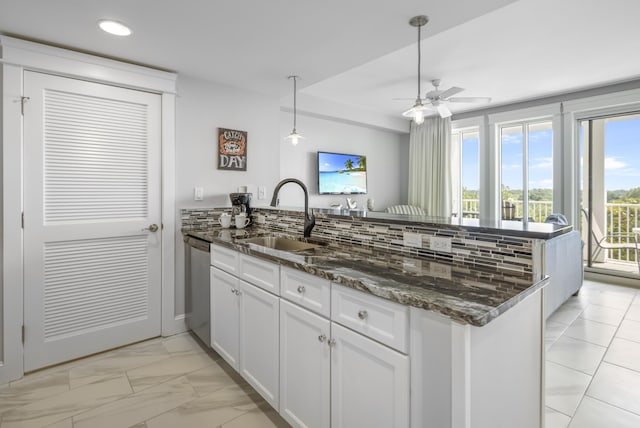 kitchen featuring kitchen peninsula, dark stone counters, sink, dishwasher, and white cabinetry