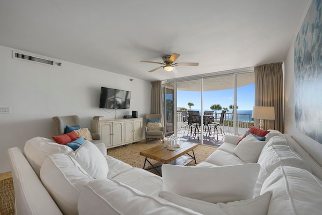 living room featuring ceiling fan, expansive windows, and light carpet