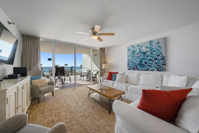 living room featuring ceiling fan, a water view, and a wall of windows