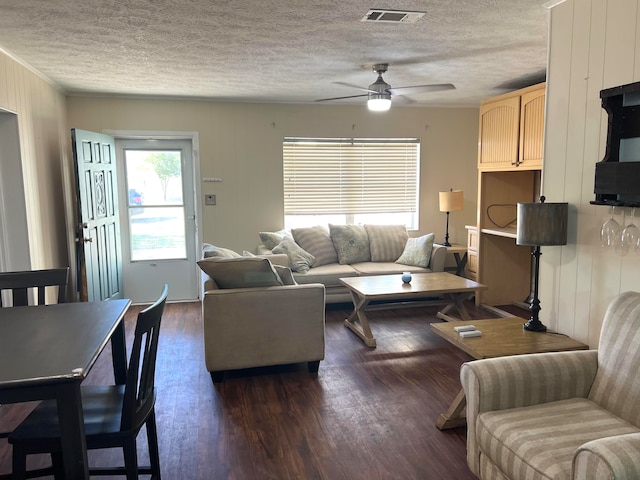 living room with a textured ceiling, dark hardwood / wood-style floors, and ceiling fan