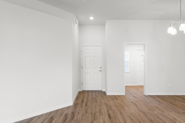 unfurnished room featuring a chandelier and wood-type flooring