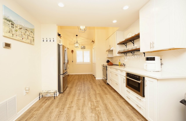 kitchen with white cabinets, appliances with stainless steel finishes, light hardwood / wood-style floors, and decorative light fixtures