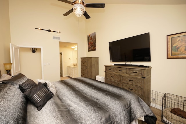 bedroom with ensuite bath, ceiling fan, wood-type flooring, and a high ceiling