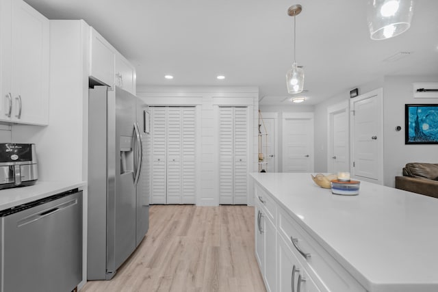 kitchen with white cabinets, pendant lighting, stainless steel appliances, and light hardwood / wood-style flooring