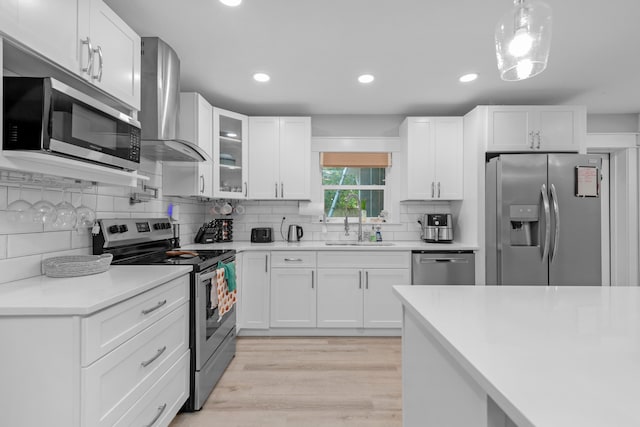 kitchen featuring white cabinetry, sink, wall chimney exhaust hood, and appliances with stainless steel finishes