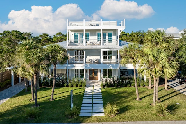 view of front of house featuring a balcony, french doors, and a front yard