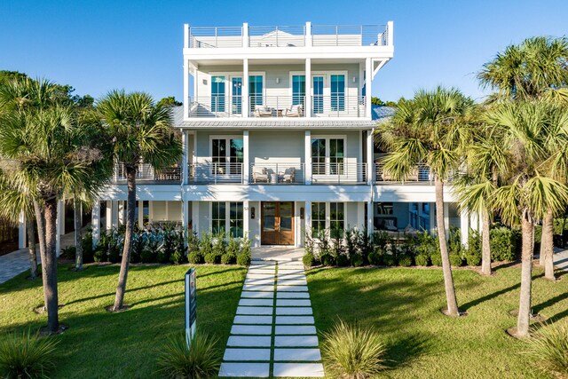 raised beach house with french doors, a balcony, and a front lawn