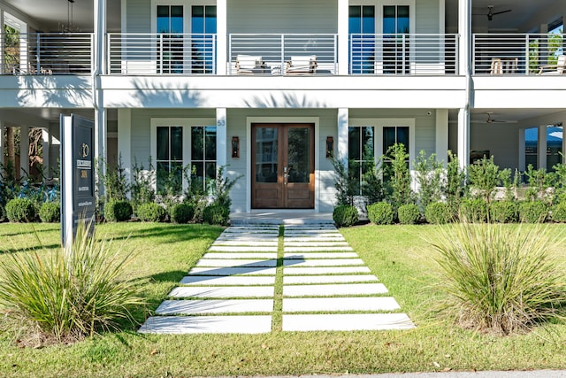 property entrance with a lawn, a balcony, and french doors