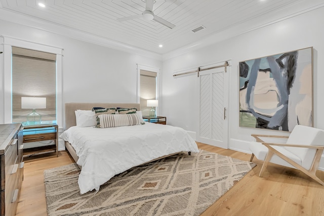 bedroom featuring a barn door, light hardwood / wood-style floors, ceiling fan, and wood ceiling