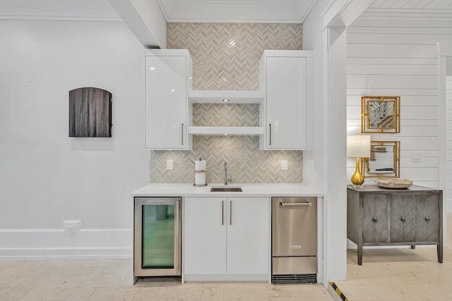 kitchen with backsplash, white cabinets, beverage cooler, and ornamental molding