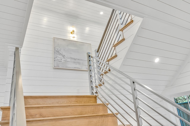 staircase with wood walls and vaulted ceiling