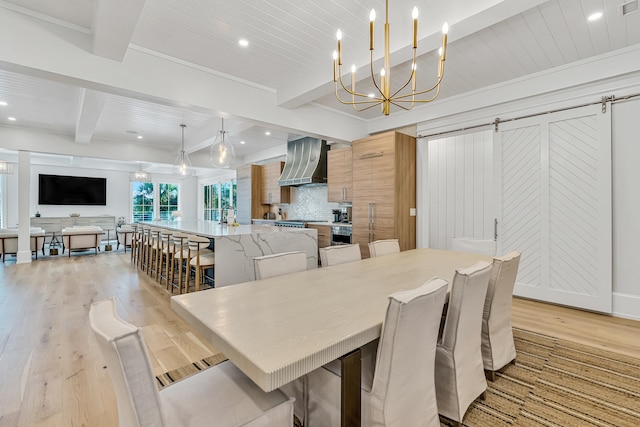 dining area with a barn door, beamed ceiling, a notable chandelier, crown molding, and light wood-type flooring