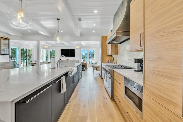 kitchen featuring pendant lighting, wall chimney range hood, light hardwood / wood-style flooring, light stone countertops, and stainless steel appliances