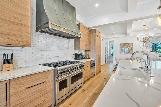 kitchen featuring sink, wall chimney exhaust hood, light stone countertops, light wood-type flooring, and stainless steel appliances