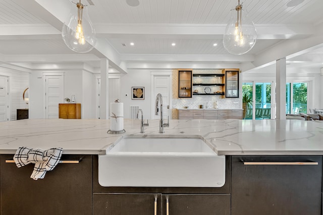 kitchen featuring dishwasher, sink, beamed ceiling, decorative light fixtures, and light stone counters