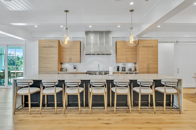 kitchen with a breakfast bar area, a large island, hanging light fixtures, and light stone counters