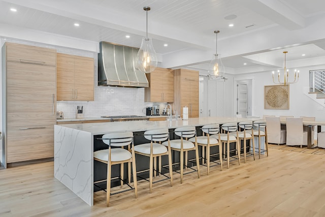 kitchen featuring a large island with sink, pendant lighting, and custom exhaust hood