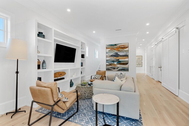 living room featuring built in shelves, crown molding, and hardwood / wood-style flooring