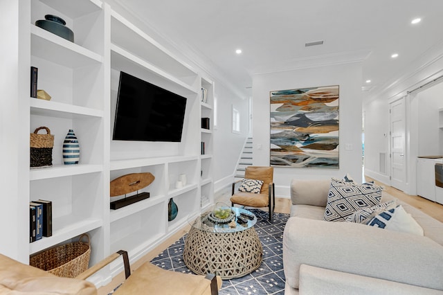 living room with hardwood / wood-style floors, built in shelves, and crown molding