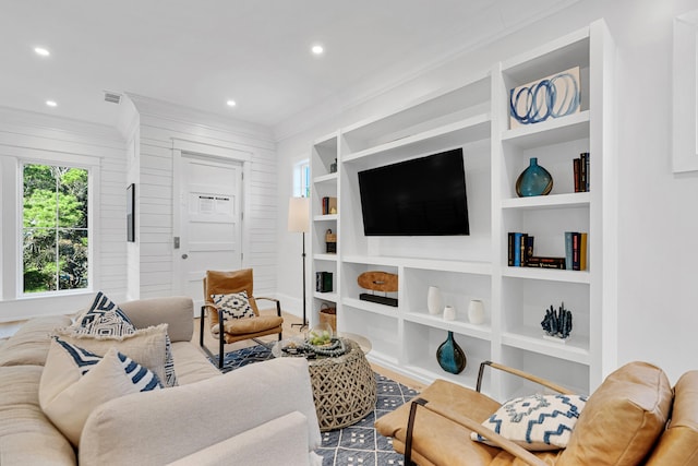 living room featuring hardwood / wood-style floors, built in shelves, and crown molding