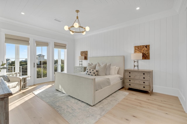 bedroom with wood walls, light hardwood / wood-style flooring, ornamental molding, and a notable chandelier