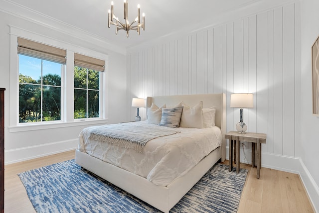 bedroom with light wood-type flooring, ornamental molding, and an inviting chandelier