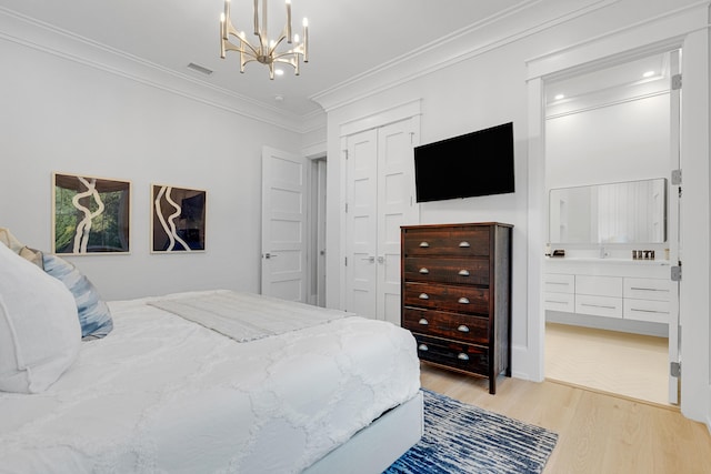 bedroom featuring light wood-type flooring, crown molding, connected bathroom, and a chandelier