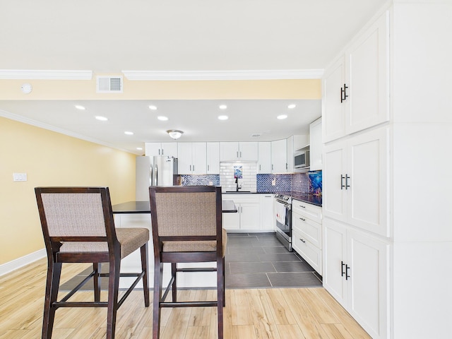 151 Calhoun Ave Unit 301, Destin, FL 32541 - kitchen with visible vents, crown molding, wood finished floors, stainless steel appliances, and white cabinetry