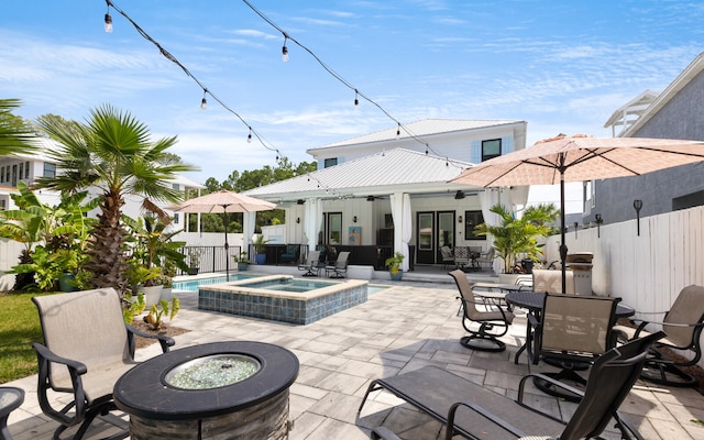 view of patio with ceiling fan, a pool with hot tub, and a fire pit