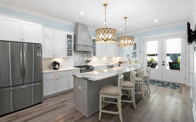 kitchen with white cabinets, a kitchen island, stainless steel appliances, and custom range hood