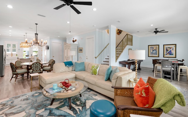 living room featuring ceiling fan with notable chandelier, light hardwood / wood-style floors, and ornamental molding