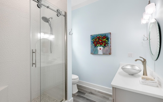 bathroom featuring toilet, vanity, an enclosed shower, and hardwood / wood-style floors