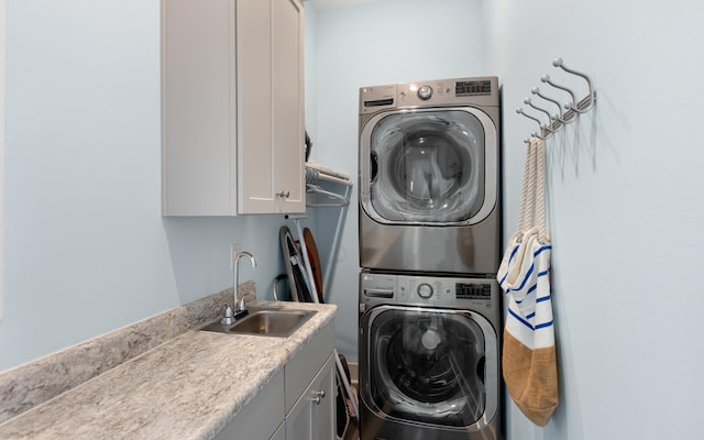 washroom with cabinets, stacked washer and clothes dryer, and sink