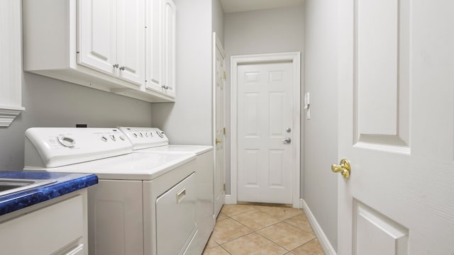 laundry area with cabinets, light tile patterned floors, and washing machine and clothes dryer