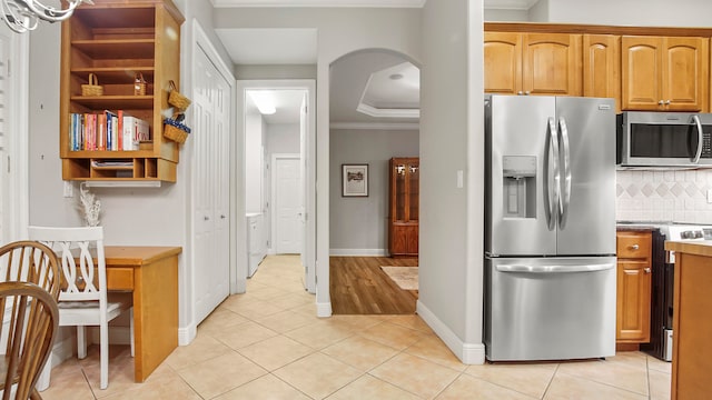 kitchen with decorative backsplash, appliances with stainless steel finishes, light tile patterned floors, and ornamental molding